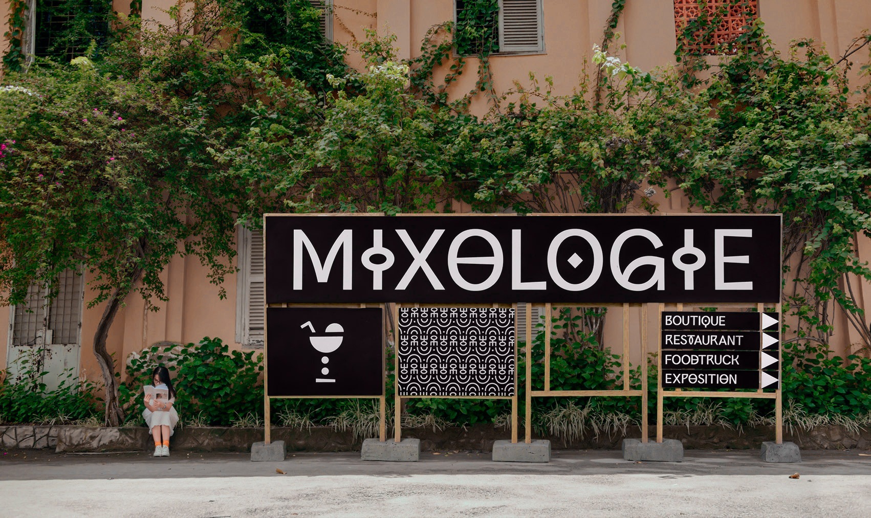 Photo montrant un grand panneaux de signalétiques qui informe que l'on se trouve au stand mixologie et indique la direction d'autre stands du festival L’Afrique c’est chic.