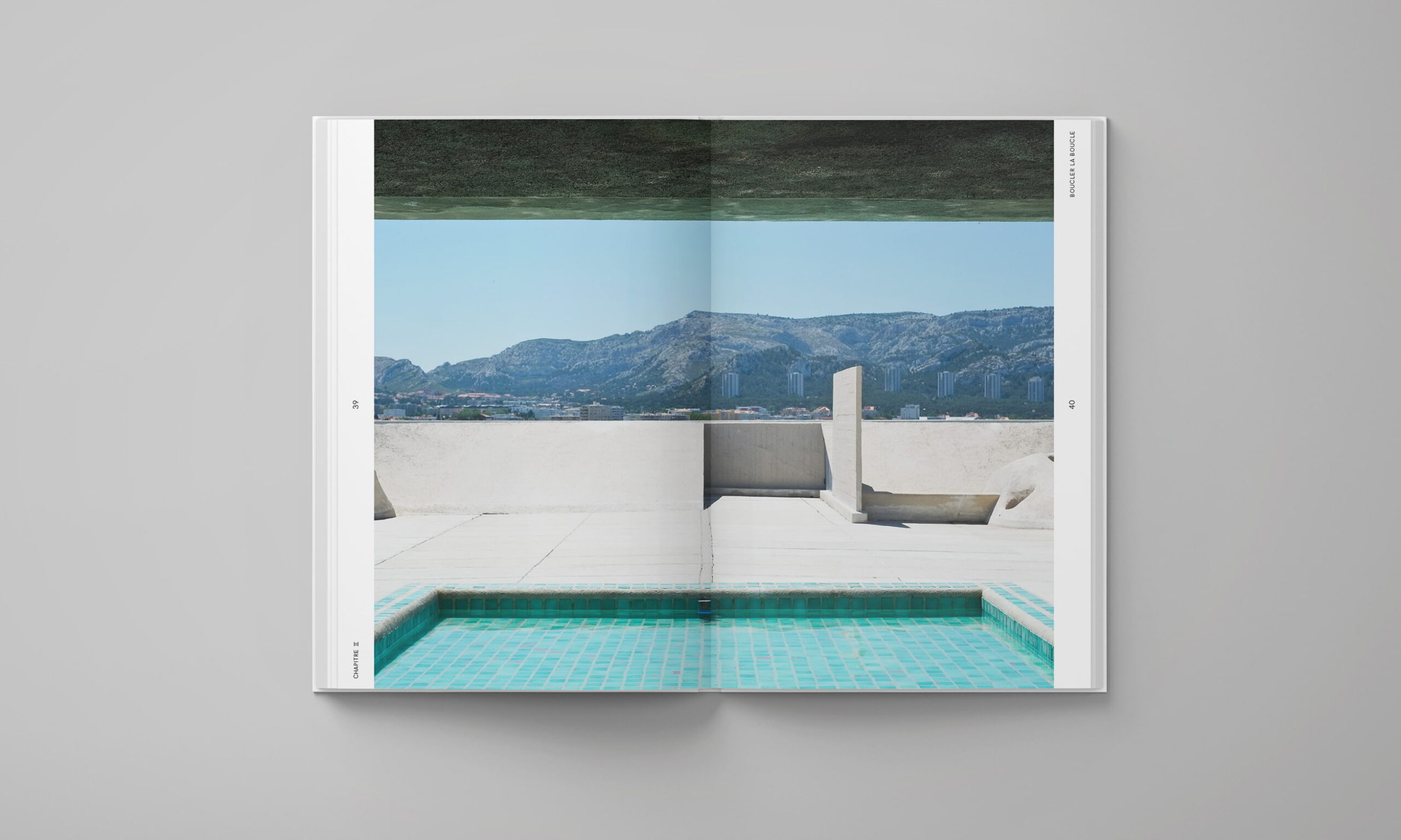Double page du livre Biomimesis présentant une photographie d’une piscine turquoise sur une terrasse, avec des montagnes à l’horizon.